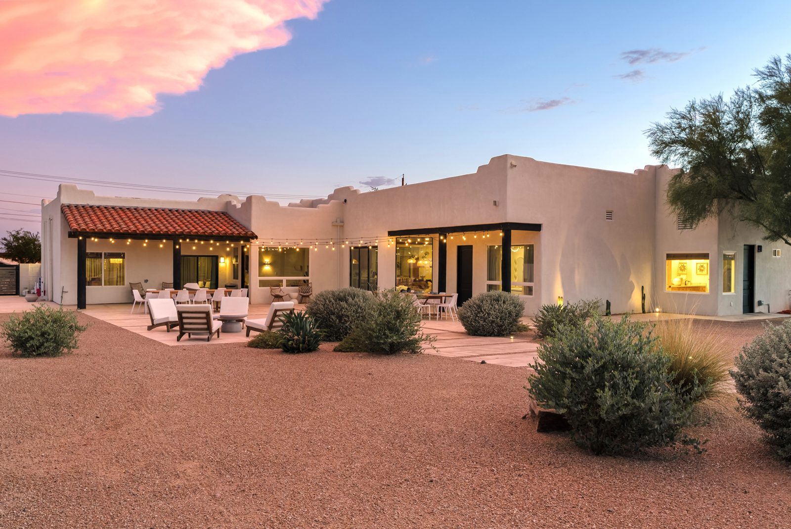 La Serena lit from inside at twilight on its one acre in Apache Junction, with the Superstition Mountains behind the house